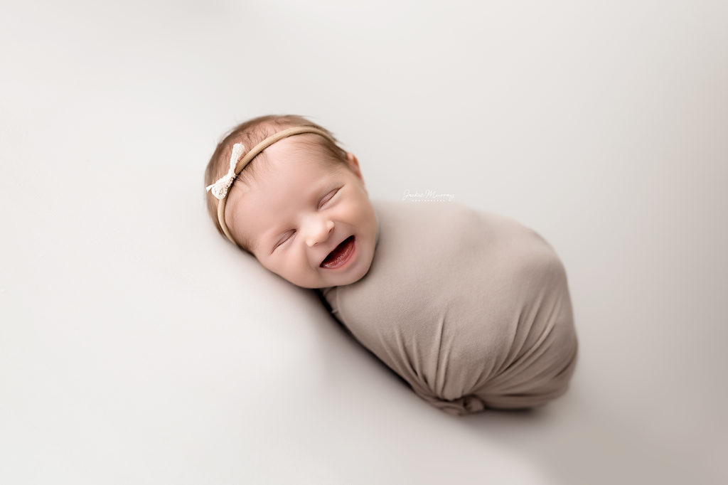 Newborn baby girl smiles during her photo session in a studio near Birmingham