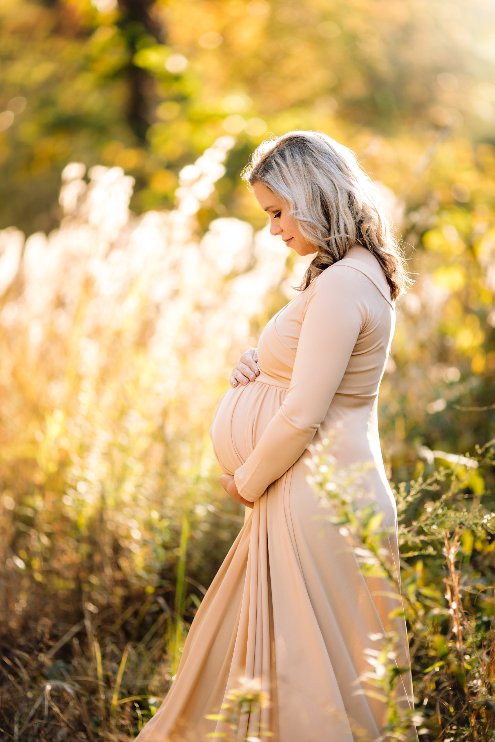 maternity photoshoot in tall grass during golden hour