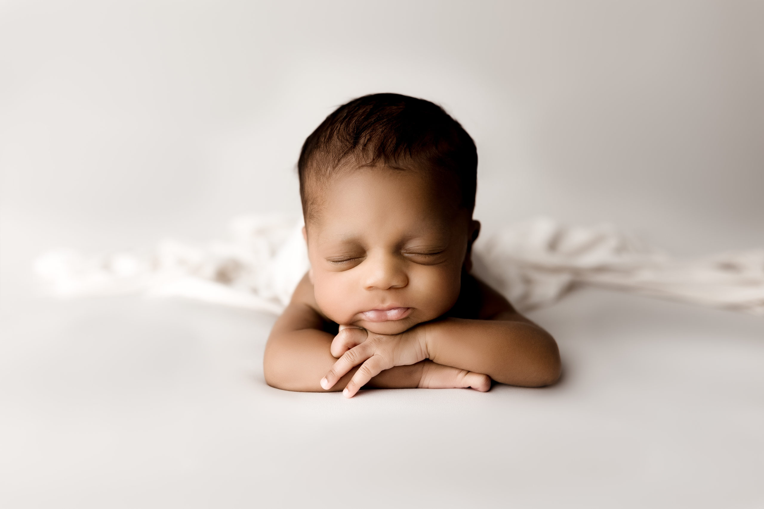 Newborn boy with head on hands in photography studio near Birmingham